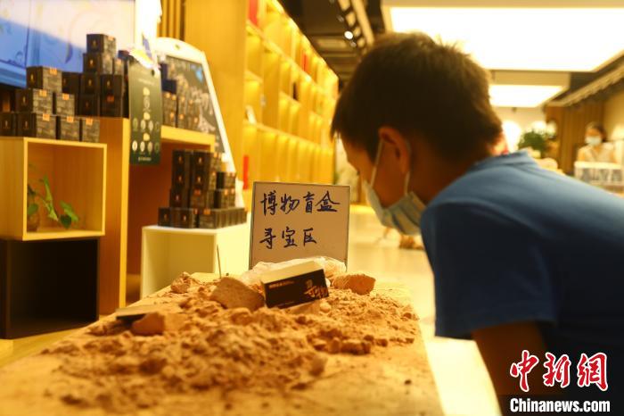 圖為在江西省博物館天工坊，一名小男孩端詳著已經(jīng)拆解完畢的“考古盲盒”現(xiàn)場(chǎng)?！⒄祭?攝